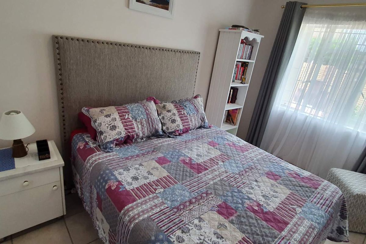 A cozy bedroom featuring tiled flooring and a window with installed curtain rails, providing natural light.