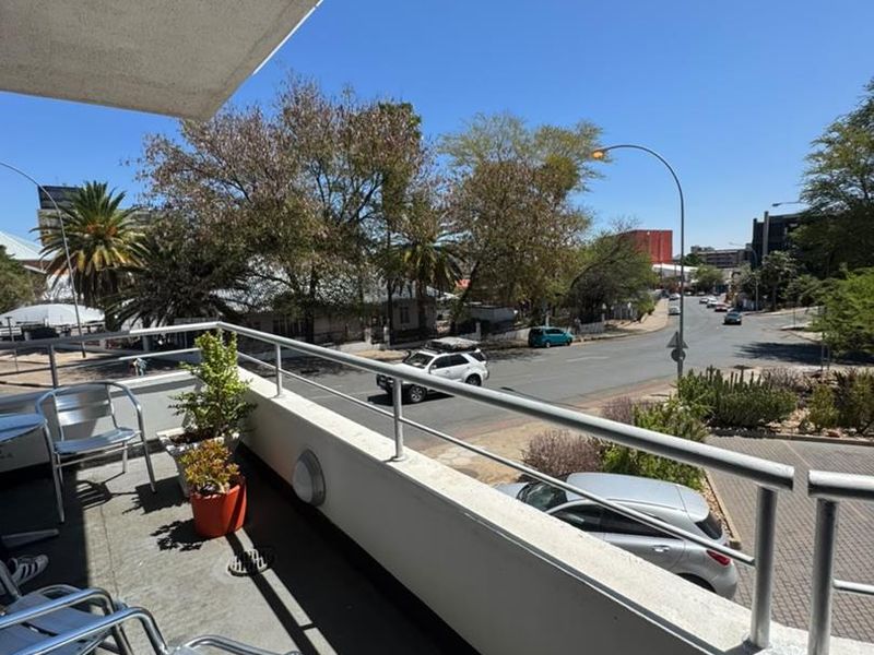 A functional balcony with metal railings, offering an elevated view of the surrounding street and neighborhood.