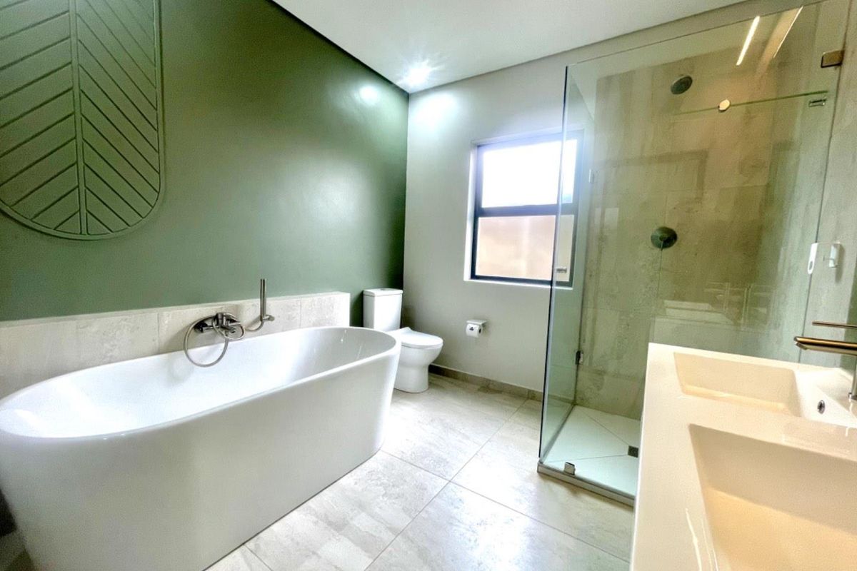 Modern bathroom featuring a freestanding bathtub, glass-enclosed walk-in shower, double vanity, and a decorative feature wall.