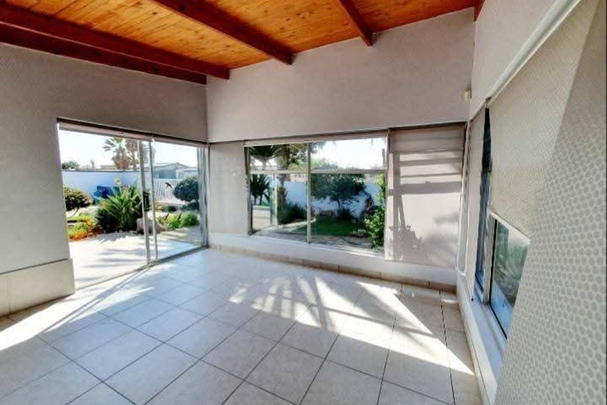 Bright and spacious living area featuring exposed timber beam ceilings, tiled flooring, and large sliding glass doors providing direct access to the garden.