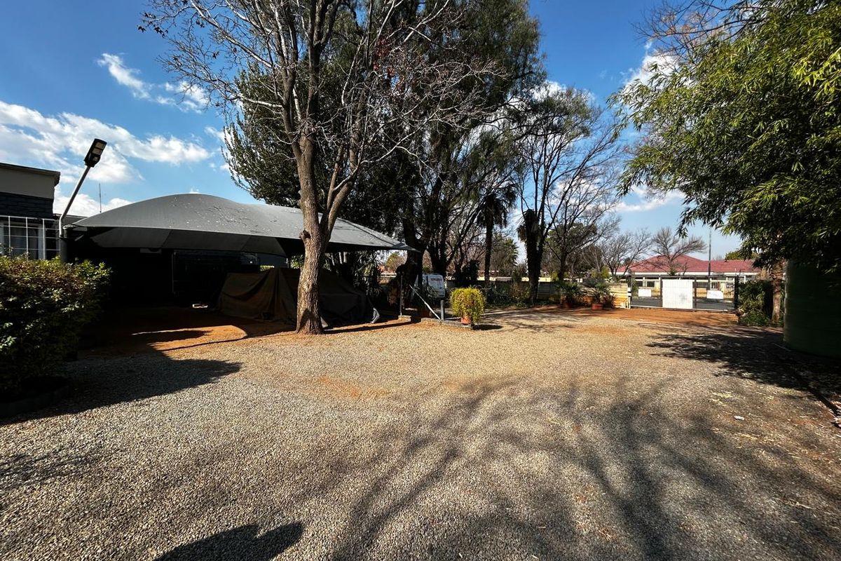 Spacious outdoor area featuring a gravel driveway, shade sail structure, and secure gated access, suitable for parking or utility use.
