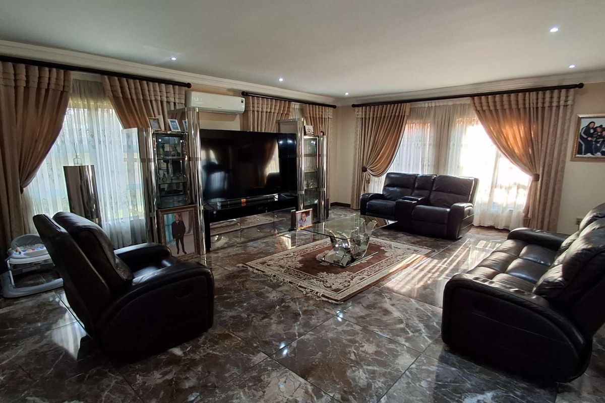 Spacious living room featuring polished marble-look floor tiles, recessed downlighting, and a wall-mounted split-system air conditioner.