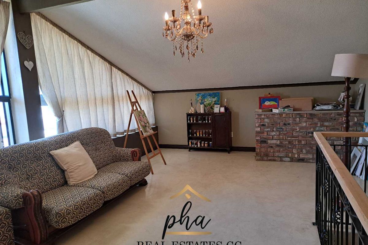 Spacious living area featuring a vaulted ceiling, exposed brick feature wall, and decorative chandelier, offering a unique architectural layout.