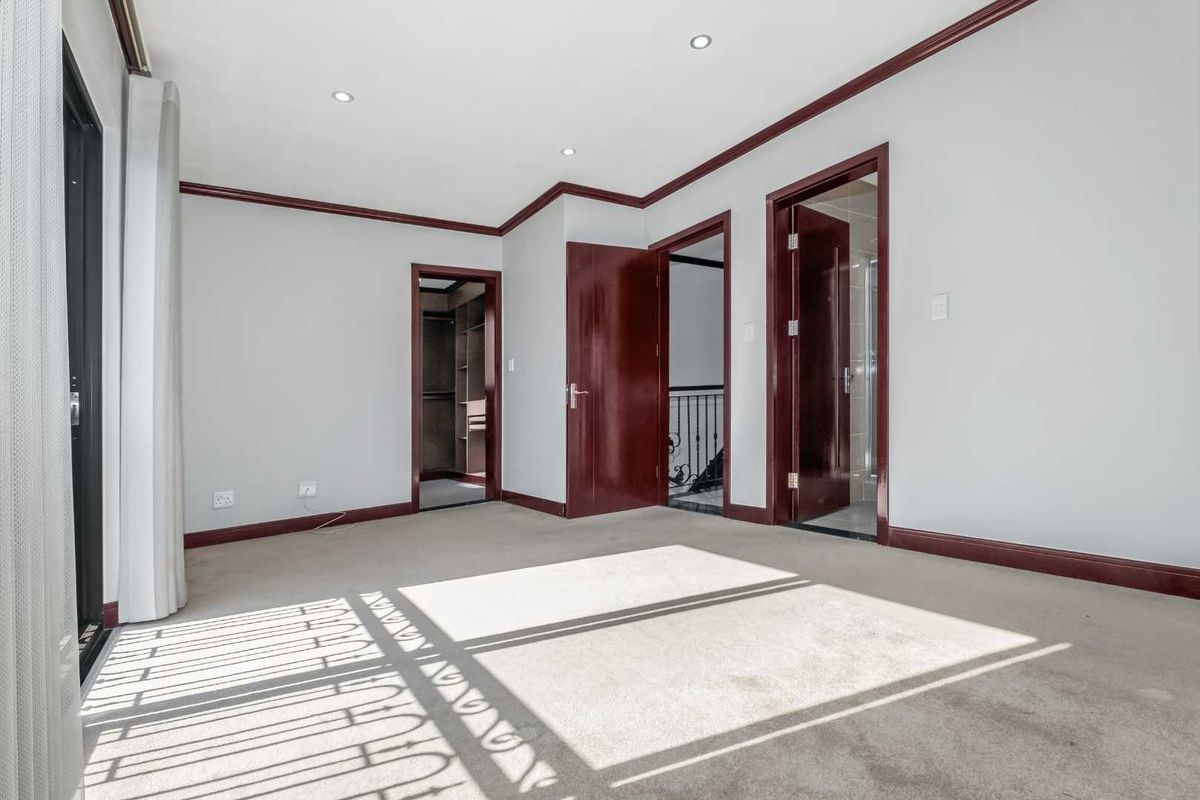 Spacious, light-filled bedroom featuring neutral walls, carpeted flooring, recessed lighting, and direct access to an en-suite bathroom and walk-in closet.
