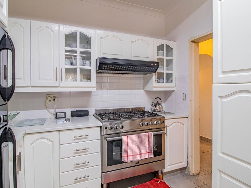 A functional kitchen featuring white cabinetry, a gas stove with an extractor fan, and a classic subway tile backsplash.