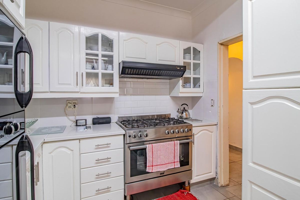 A functional kitchen featuring white cabinetry, a gas stove with an extractor fan, and a classic subway tile backsplash.