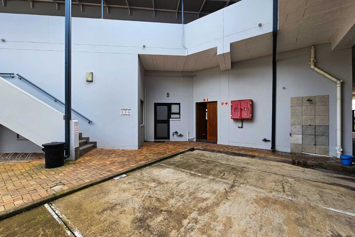 A communal outdoor area featuring paved walkways, a staircase, and a fire hose reel, providing access to building entrances.
