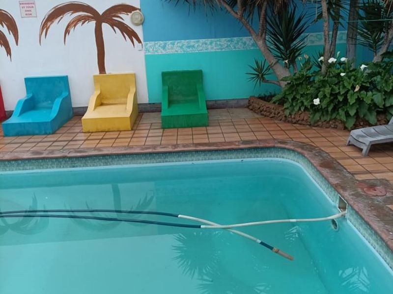 Outdoor pool area featuring a swimming pool with tiled surround and built-in seating against a painted feature wall.