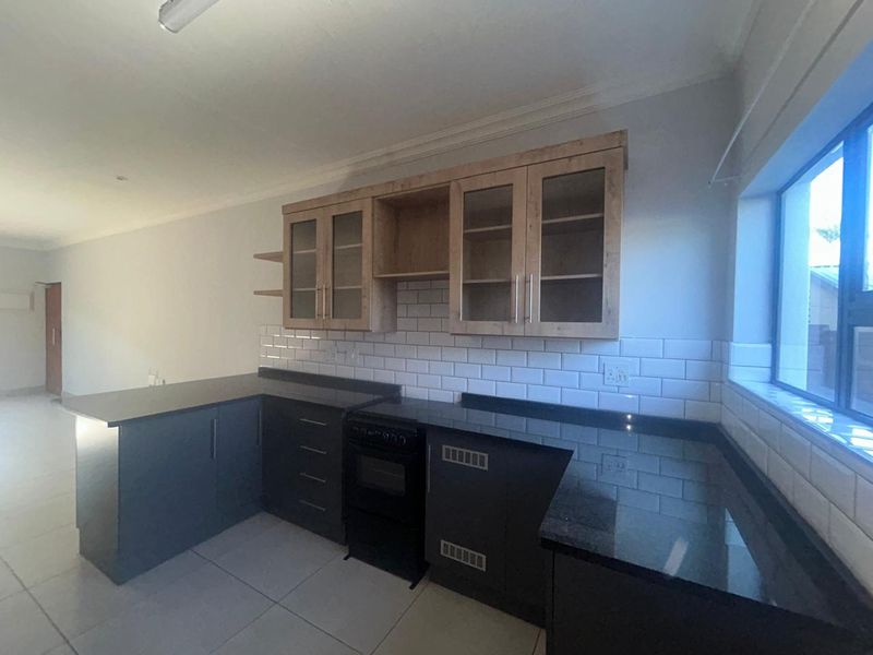 Modern kitchen featuring dark cabinetry, granite countertops, subway tile backsplash, and a freestanding oven, offering a clean and functional workspace.