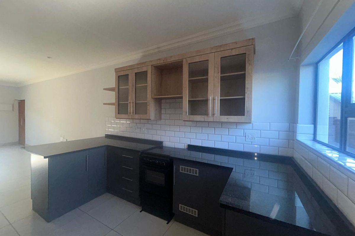 Modern kitchen featuring dark cabinetry, granite countertops, subway tile backsplash, and a freestanding oven, offering a clean and functional workspace.