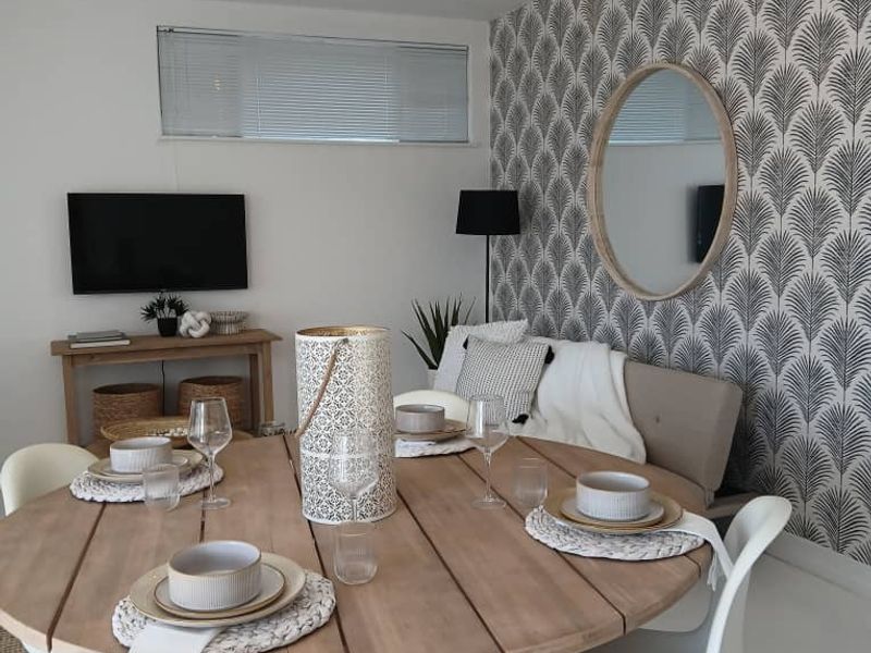 A well-presented dining area featuring a statement patterned wallpaper, modern pendant lighting, and neutral finishes, creating a warm and inviting atmosphere.