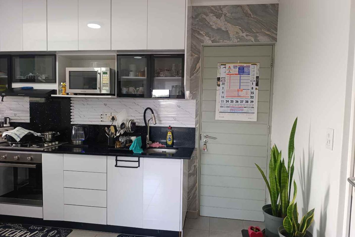 Modern kitchen featuring white high-gloss cabinetry, black granite countertops, integrated appliances, and a stylish marble-effect feature wall near the doorway.