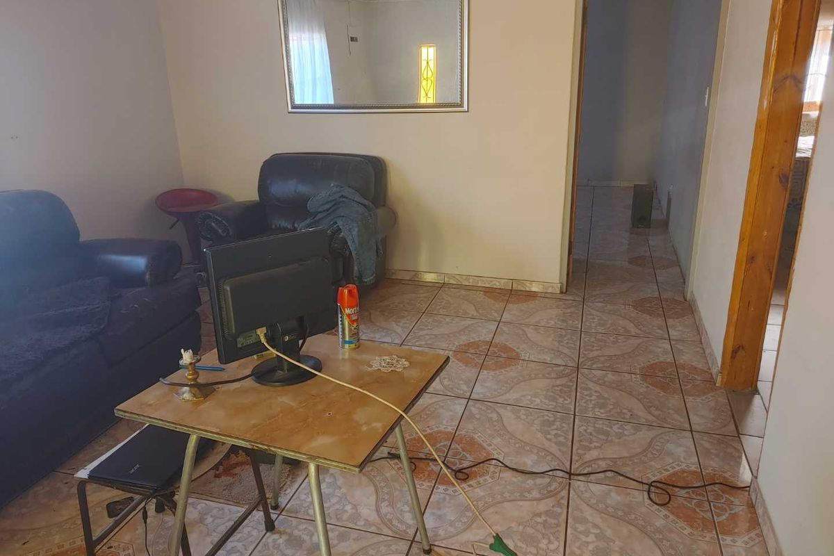 A living area featuring ceramic floor tiles and a doorway leading to an adjacent hallway.