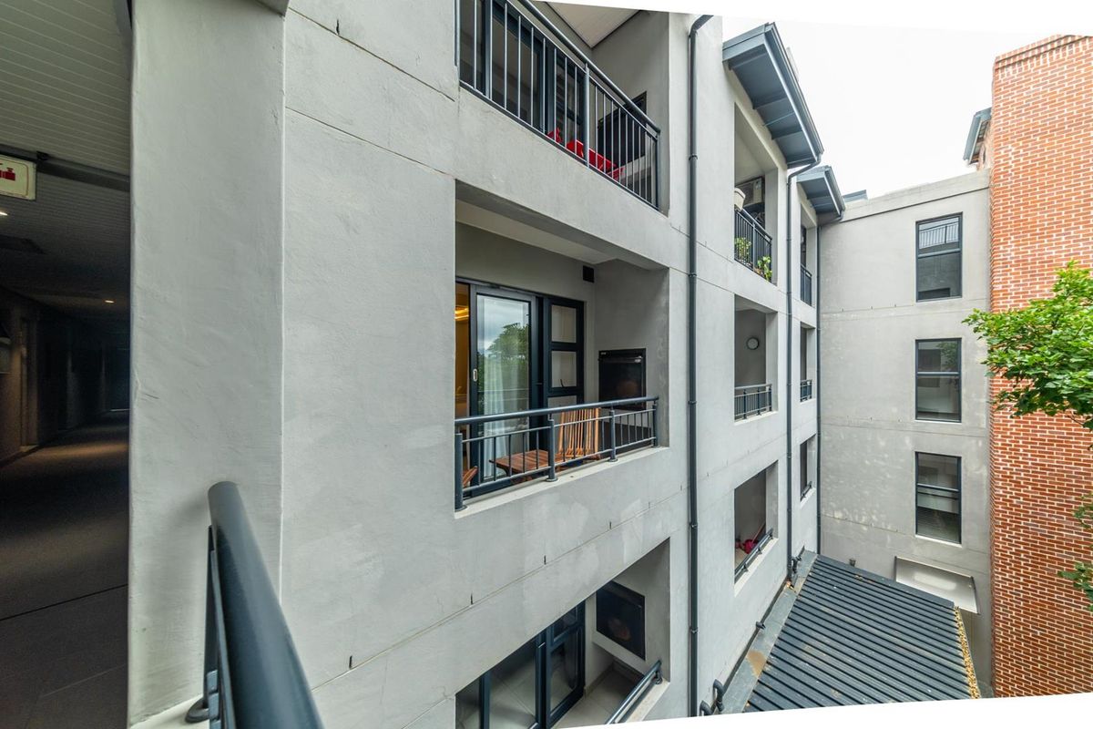 Exterior view of a modern apartment building featuring stacked balconies with metal railings and grey rendered facade finishes.