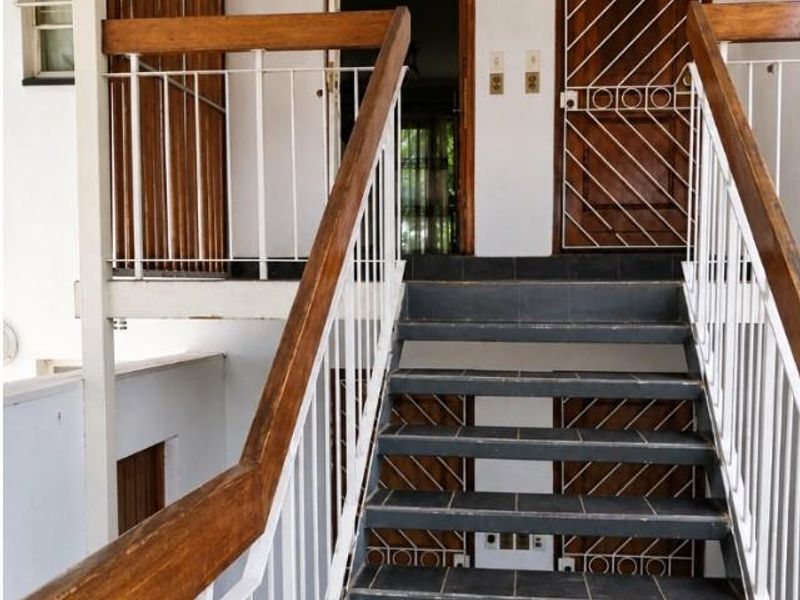 Exterior staircase leading to apartment entrance, featuring tiled steps, metal balustrades with wooden handrails, and secure entry doors.