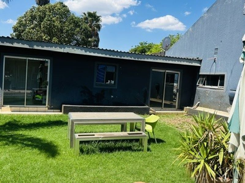 Rear exterior view of the property featuring a tiled patio area, lawn, and sliding glass doors providing access to the home.