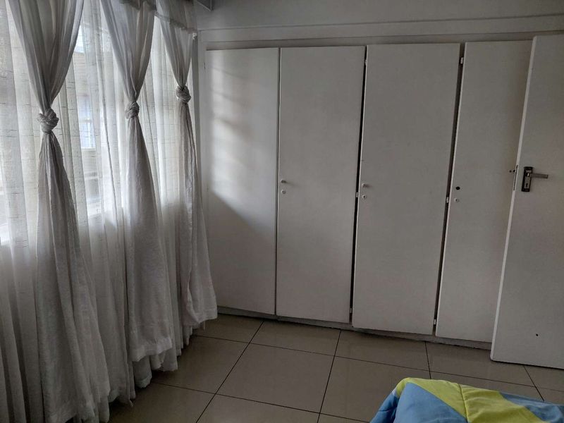 Bedroom featuring tiled flooring and built-in cupboards, offering functional storage space with natural light from the window.