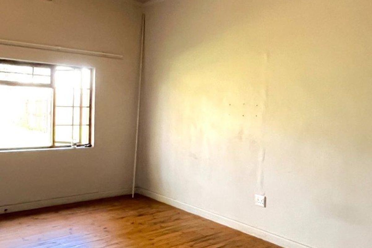 An empty bedroom featuring original timber flooring, a single window, and a painted timber ceiling.