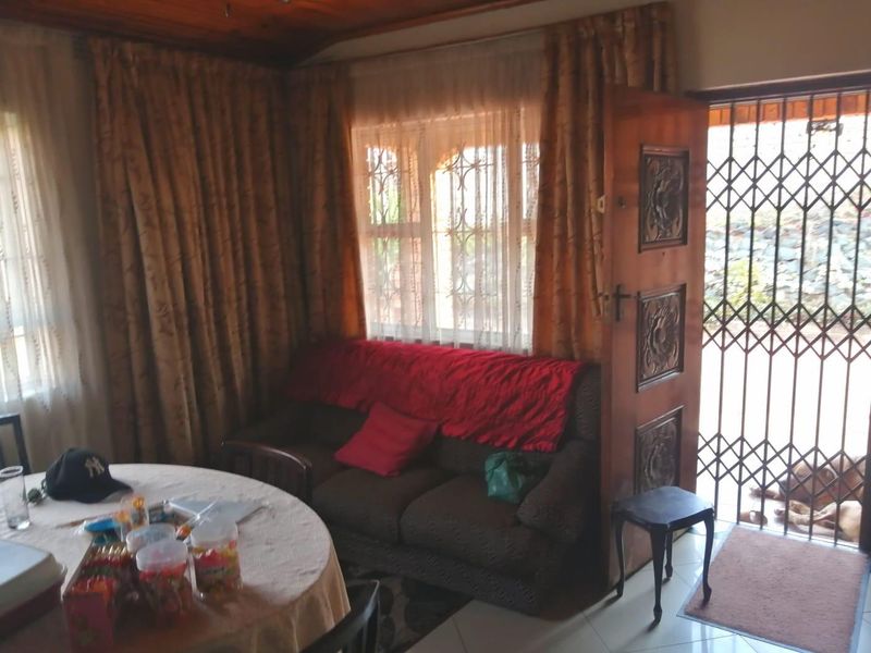 A living area featuring tiled flooring, a timber ceiling, and a decorative carved wooden door leading to a security gate entrance.