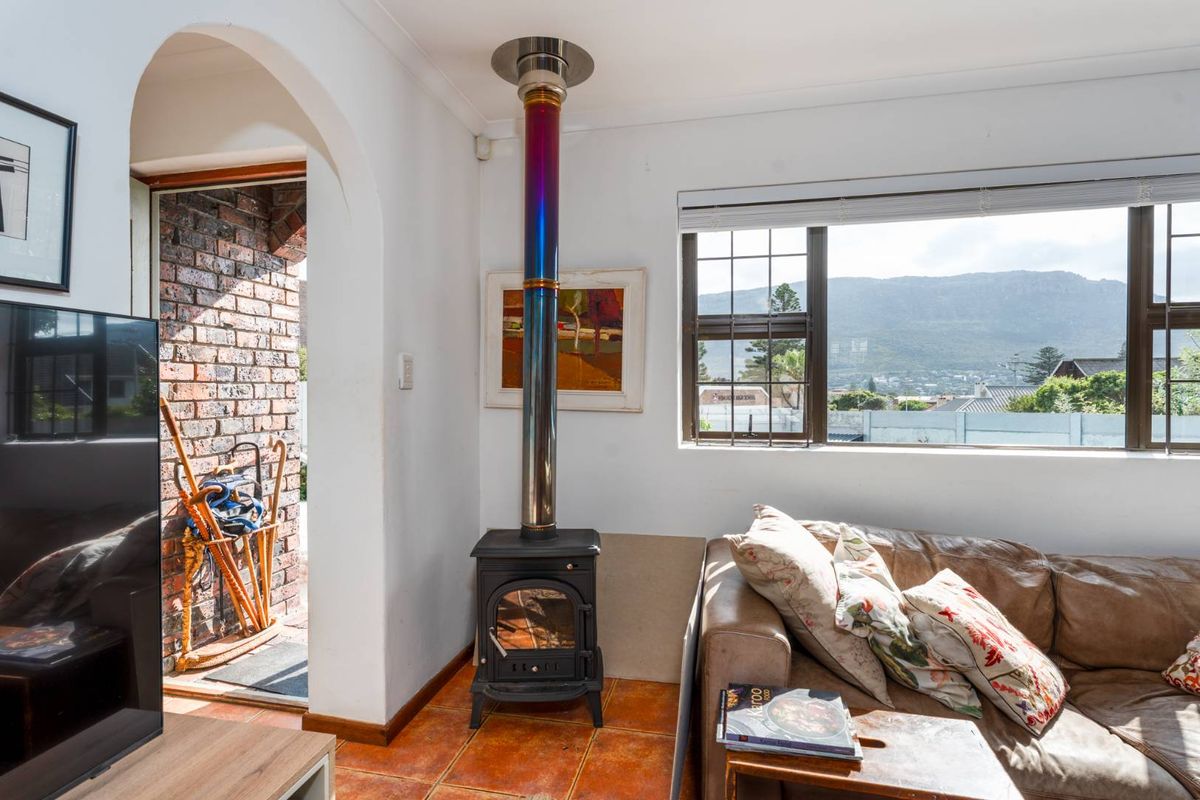 Living room featuring a freestanding cast-iron fireplace with a flue, terracotta floor tiles, and an arched doorway leading to an exterior brick patio.