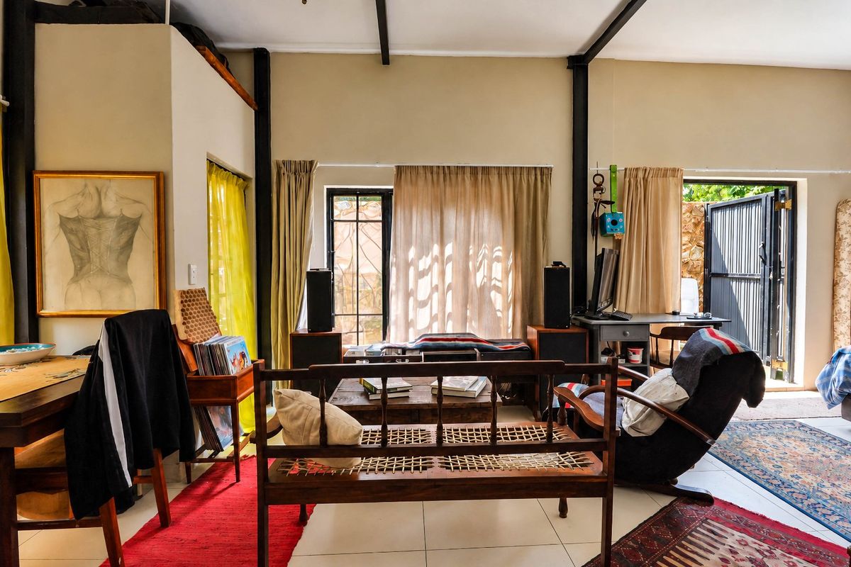 Spacious living area featuring exposed structural beams, tiled flooring, and large glass sliding doors providing direct access to the outdoor space.