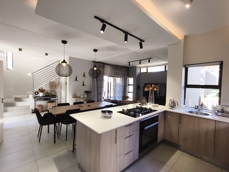Modern open-plan living area featuring a sleek kitchen with stone countertops, built-in appliances, and a seamless flow to the dining and lounge spaces.
