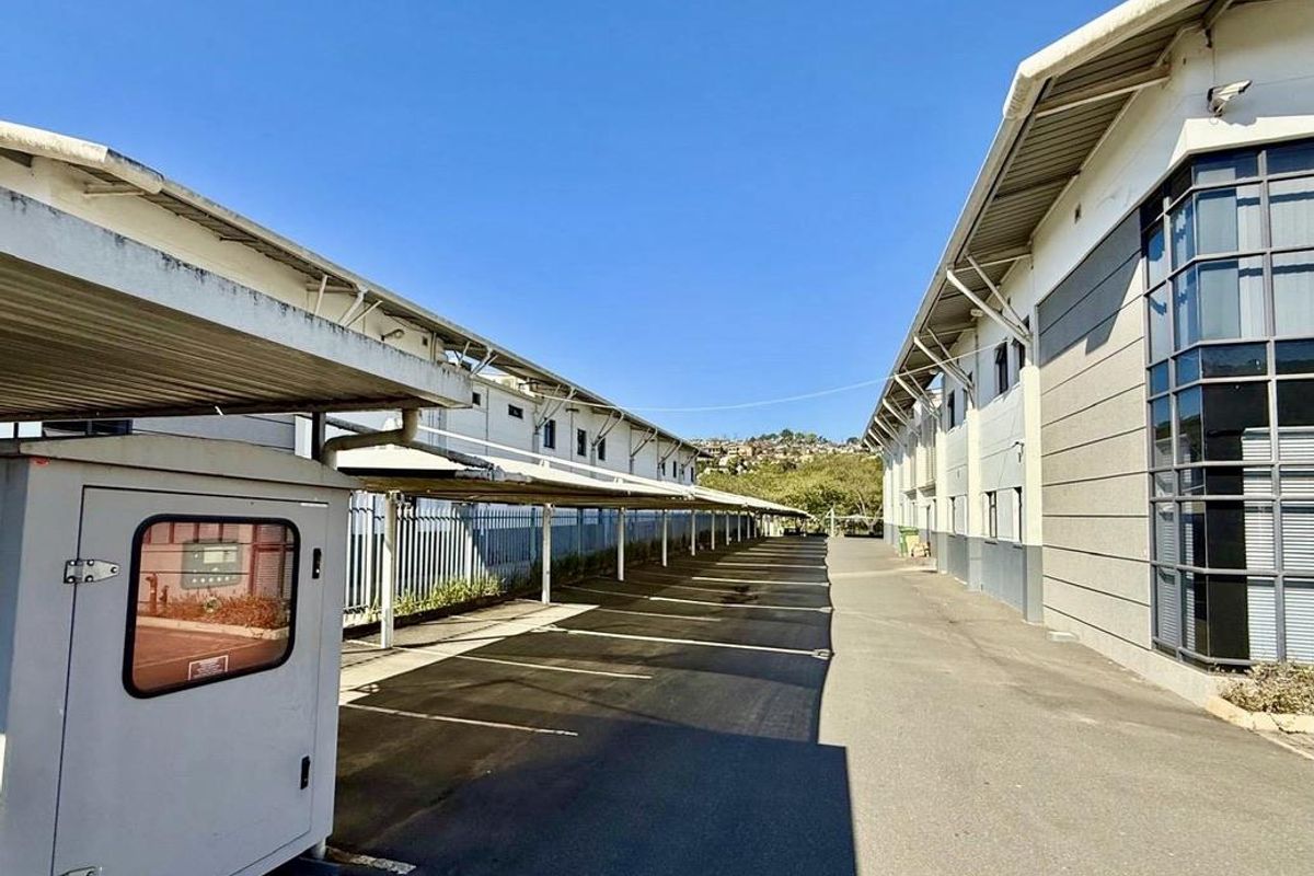 Exterior view of the office property featuring a paved parking area with covered carports and modern building facade.