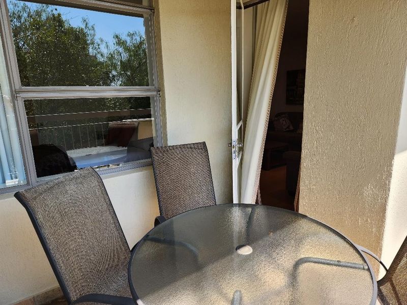 A compact balcony area featuring textured walls, a sliding window, and direct access to the interior living space.
