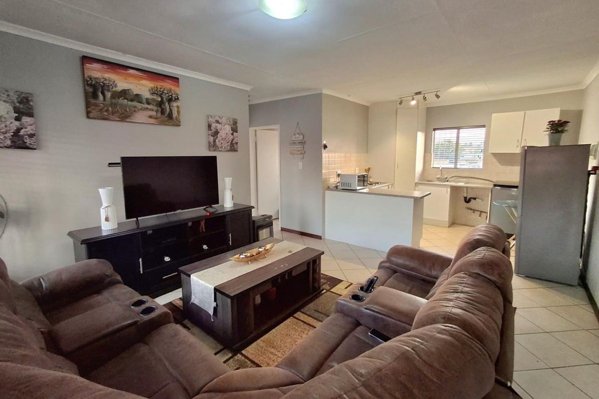 Open-plan living area featuring a combined lounge and kitchen space with tiled flooring and functional cabinetry.