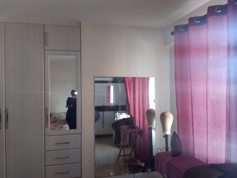 A bedroom featuring built-in wardrobes with integrated mirror panels and a large wall-mounted mirror, providing ample storage and reflective surfaces.