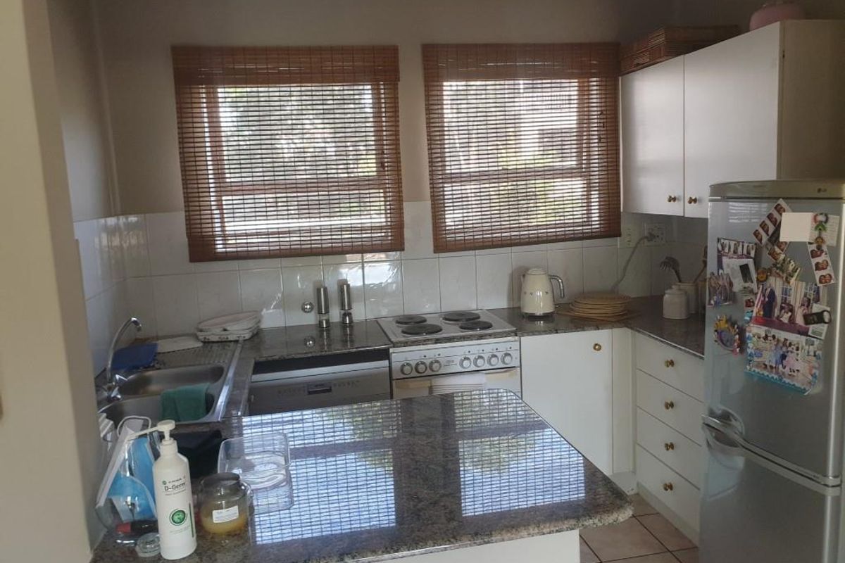 Functional kitchen featuring granite countertops, built-in cabinetry, tiled backsplash, and integrated electric cooking appliances with natural light from dual windows.