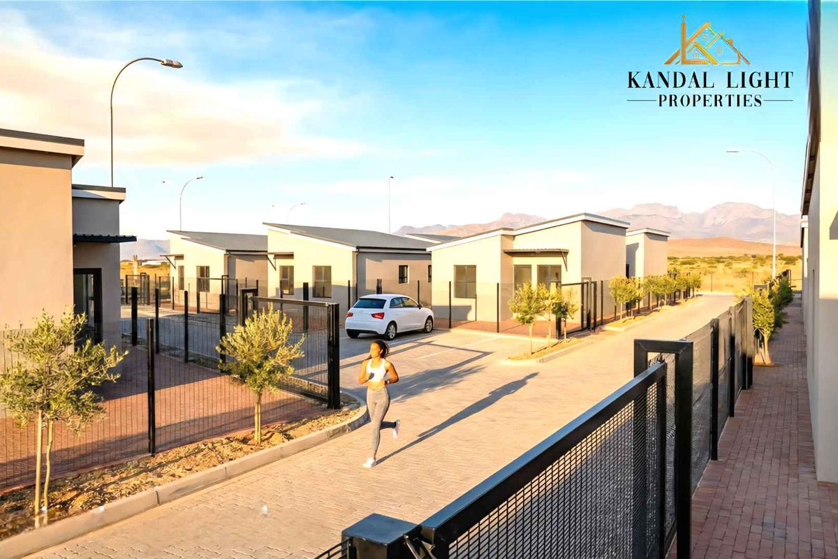 A view of a modern townhouse complex featuring paved driveways, secure perimeter fencing, and contemporary architectural design.