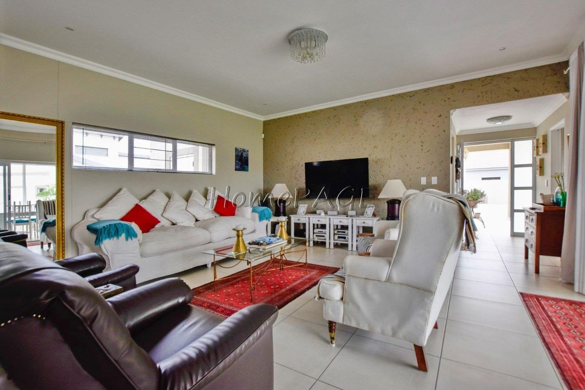 Spacious living room featuring tiled flooring, recessed lighting, and a feature wall, providing a comfortable and functional area for relaxation.