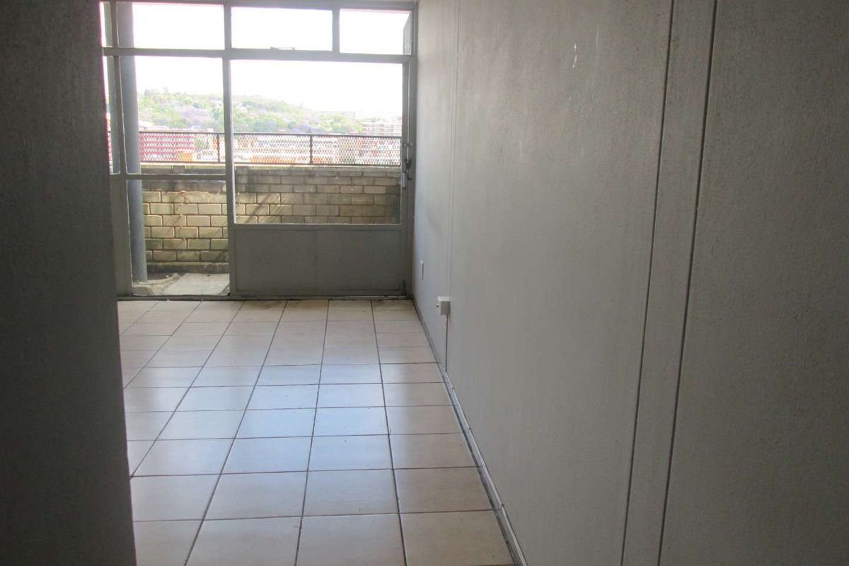 An empty living area featuring tiled flooring and a large sliding glass door leading to an outdoor balcony space.