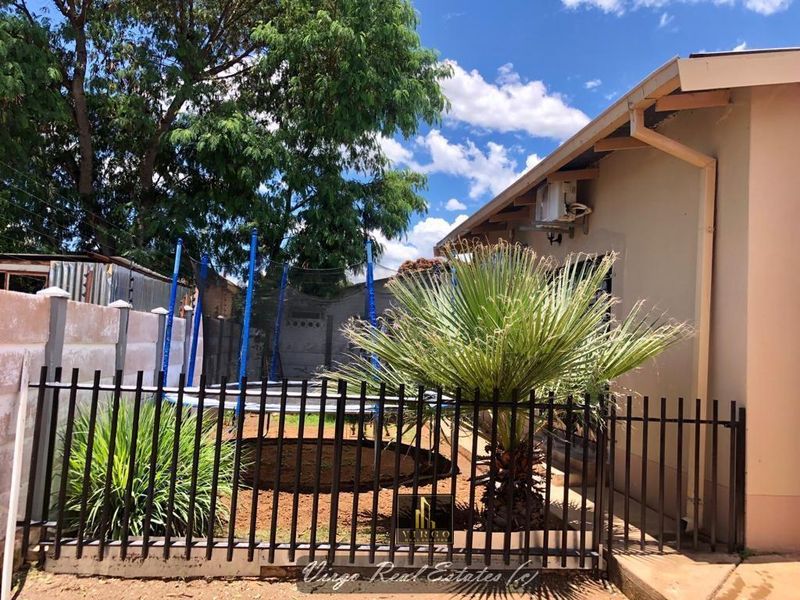 A view of the rear exterior area featuring a perimeter wall, metal fencing, and guttering along the building facade.