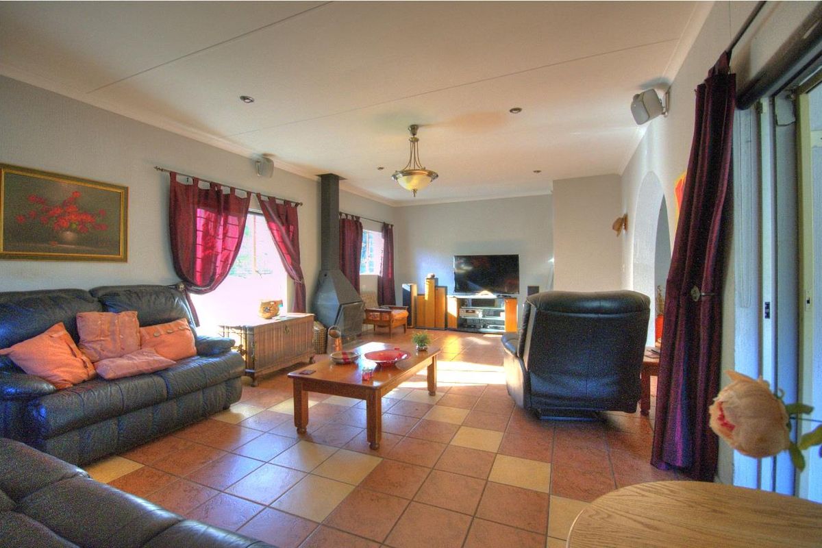 Spacious living room featuring terracotta floor tiles, a built-in fireplace, and recessed ceiling lighting, providing a comfortable and functional family living space.