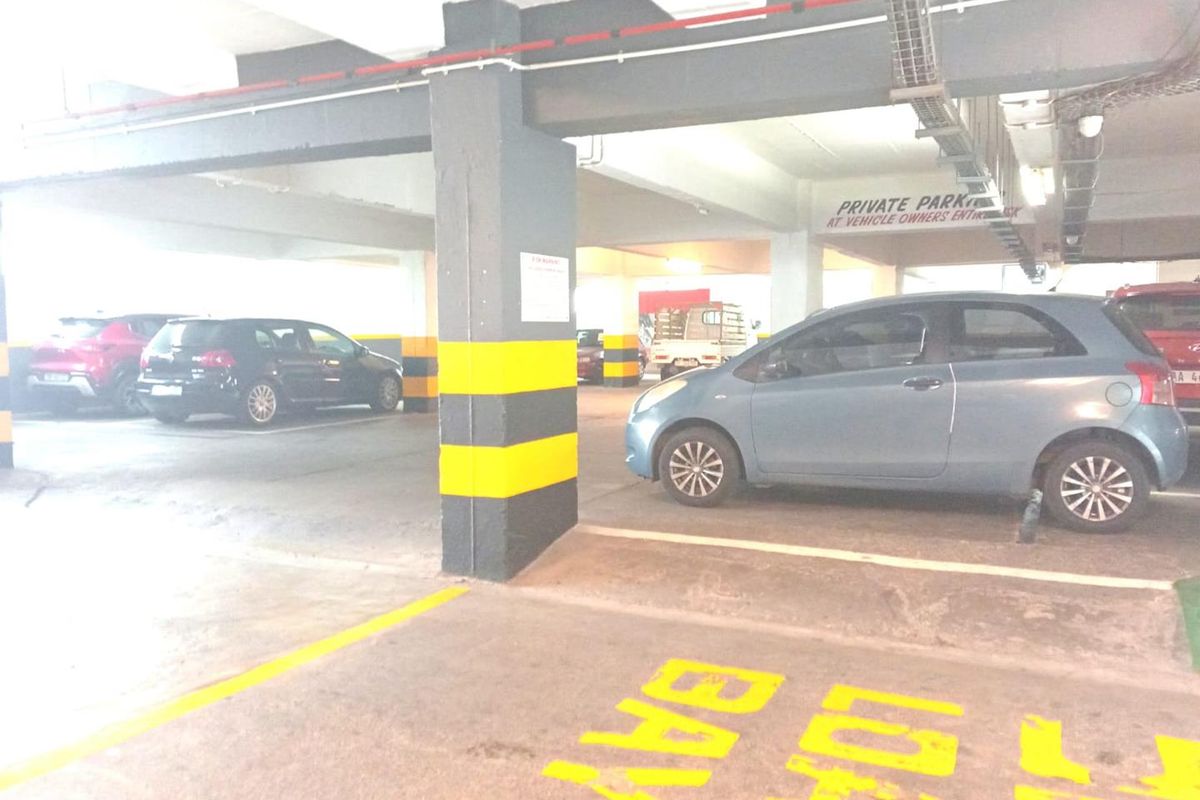 Covered parking garage area featuring concrete structural columns, overhead cable management systems, and designated parking bay markings.