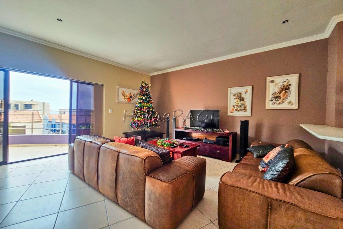 Spacious living room featuring tiled flooring, recessed ceiling lighting, and large sliding glass doors providing access to an outdoor balcony area.
