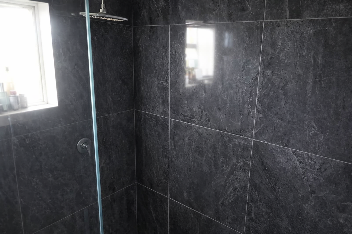 Modern bathroom shower enclosure featuring dark grey marble-effect wall tiles, a rainfall shower head, and a glass partition.
