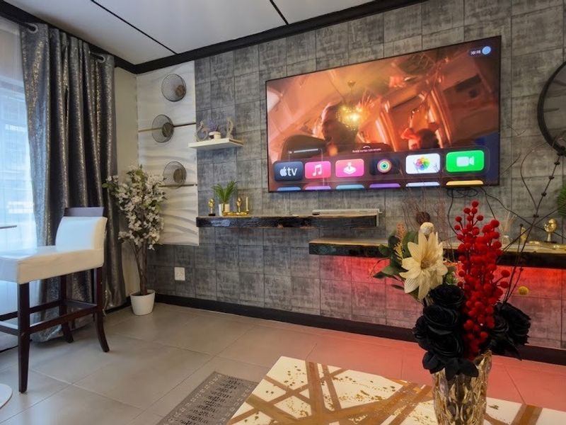 A modern living room featuring textured wall cladding, floating shelves with integrated LED lighting, and large-format floor tiles.