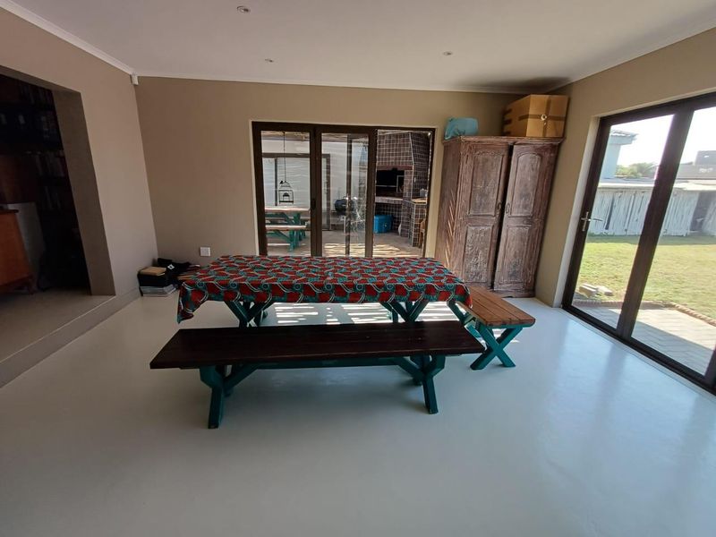 Spacious living area featuring smooth epoxy flooring, recessed lighting, and large sliding glass doors providing direct access to the outdoor patio and garden.