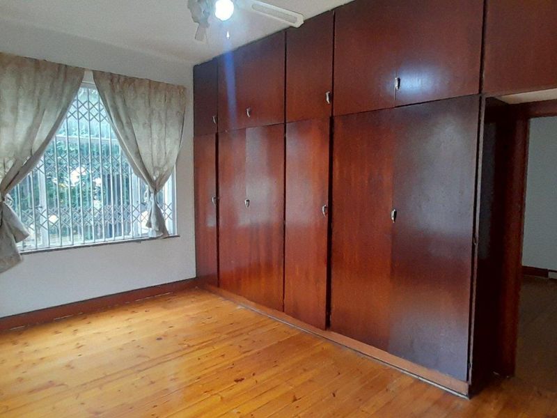 Bedroom featuring polished wooden flooring and extensive floor-to-ceiling built-in wooden cabinetry, providing ample storage space.