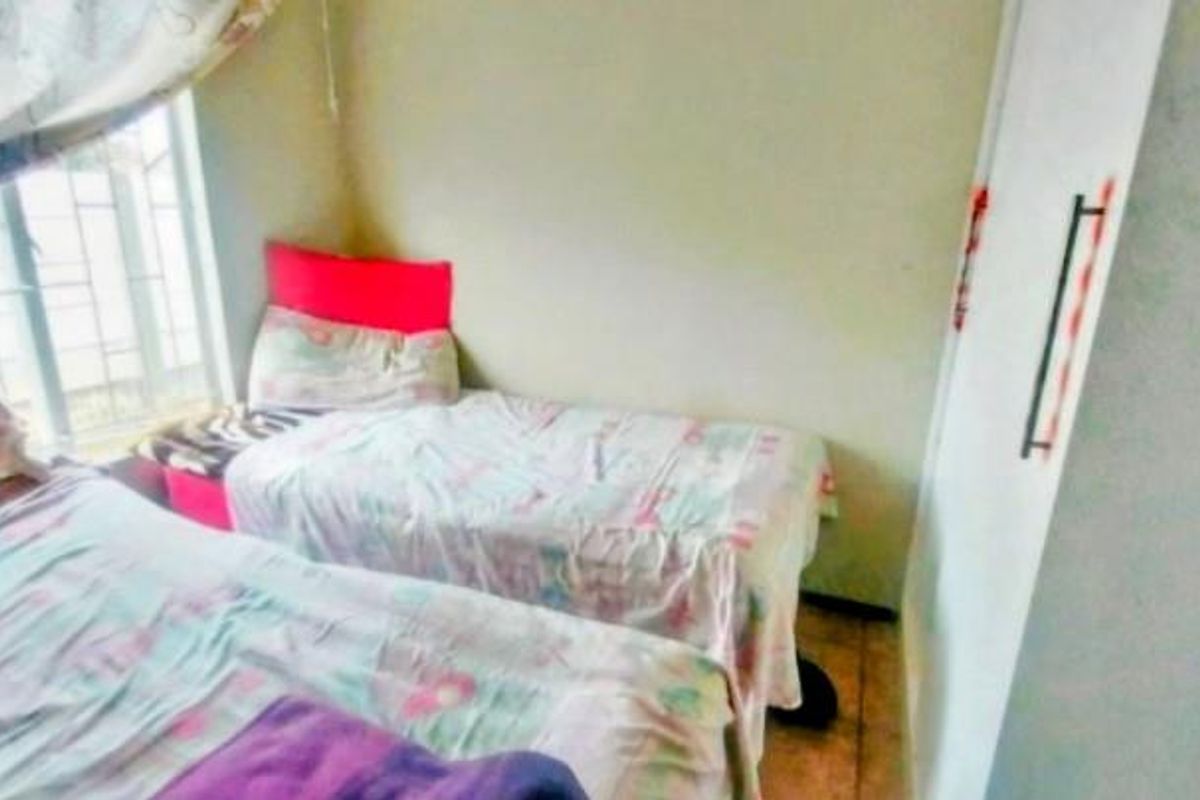 A bedroom featuring a built-in wardrobe and a window fitted with security bars.