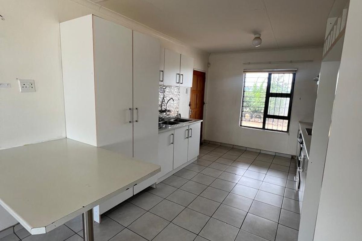 A functional kitchen featuring white cabinetry, tiled flooring, a built-in breakfast counter, and a window providing natural light.