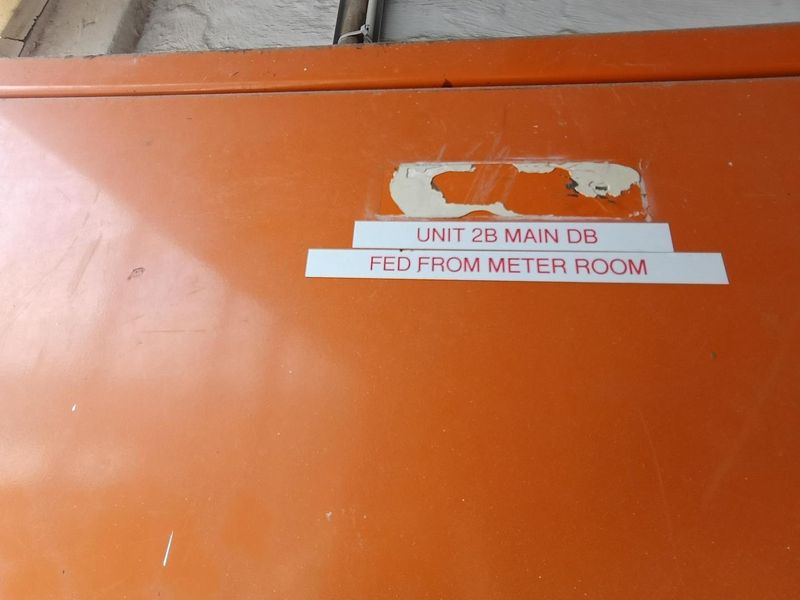 Close-up view of the Unit 2B main electrical distribution board enclosure showing surface wear and peeling paint.