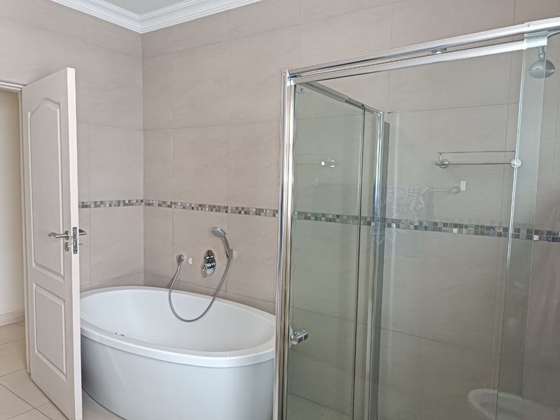 Modern bathroom featuring a freestanding bathtub, a glass-enclosed shower, and neutral wall tiling throughout.
