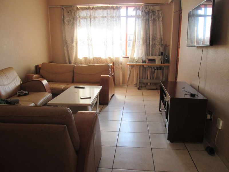 A functional living room featuring tiled flooring and a large window that allows for natural light.
