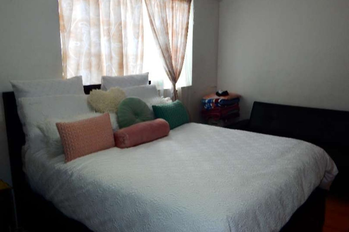 A bedroom featuring tiled flooring and a ceiling fan, providing a functional space with neutral wall finishes.