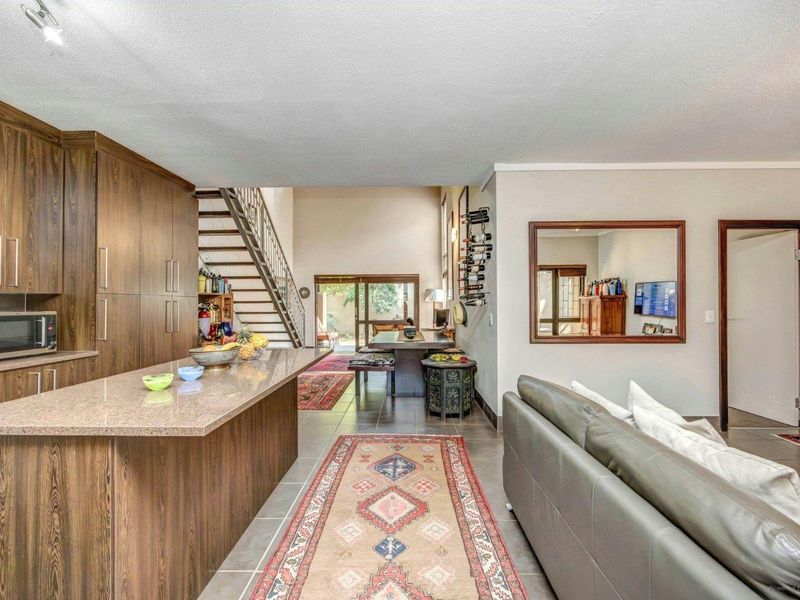 Open-plan living area featuring a modern kitchen with stone countertops, tiled flooring, and a staircase leading to the upper level.