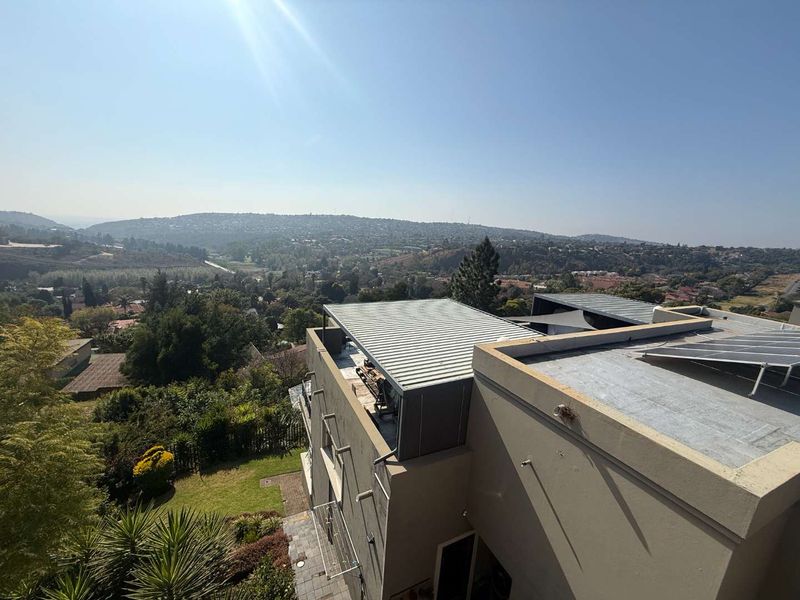 An elevated aerial view of the property showing the roof structure, solar panel installation, and expansive surrounding landscape views.